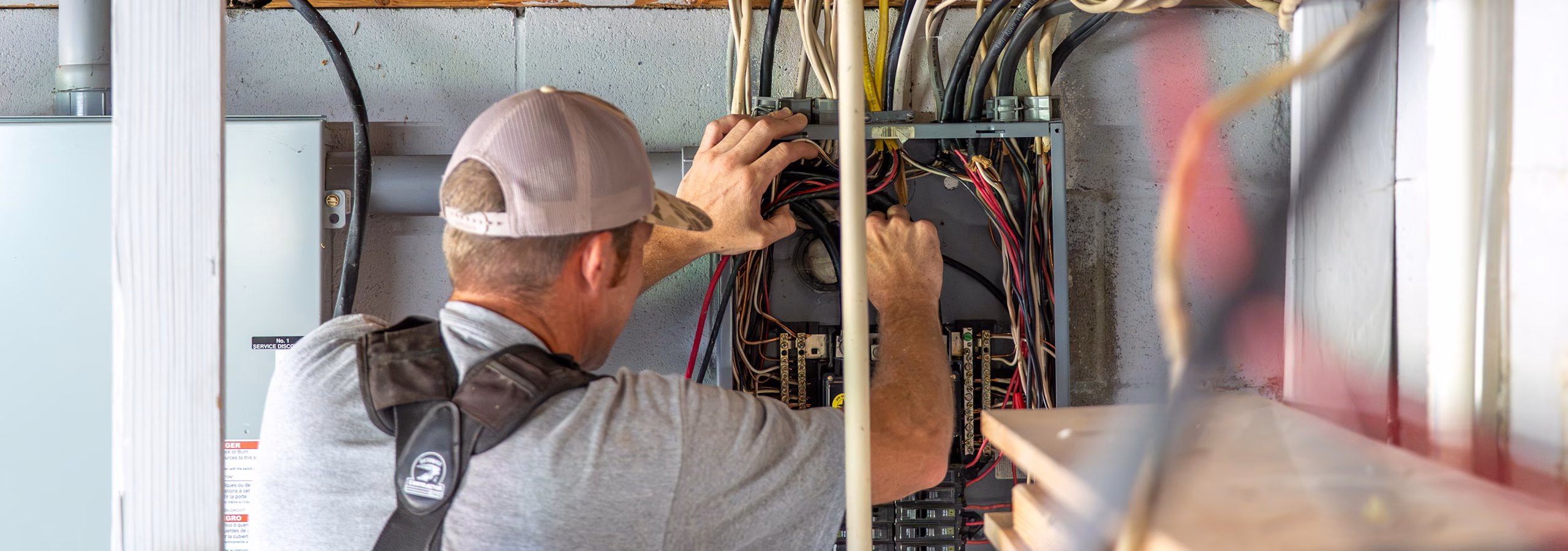 G5 Electric electrician working on an electric panel in a garage.
